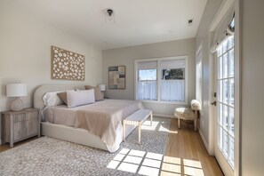A bedroom with a bed, bedside tables, a window, and a door.
