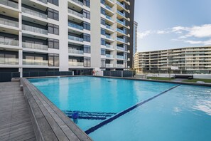 Een modern gebouw met meerdere balkons en een zwembad.