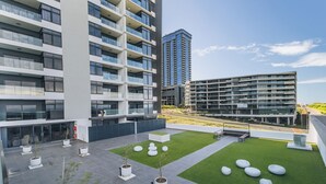 A modern building with multiple floors, outdoor seating areas, and green spaces. - Chic Umhlanga Studio | Walk to Beaches (Umhlanga)