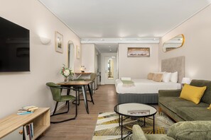 Une chambre d’hôtel moderne équipée d’un lit, d’un canapé, d’un coin repas et d’une télévision.