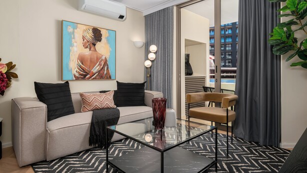 Un salon moderne avec un canapé, une table basse en verre et un tableau accroché au mur.