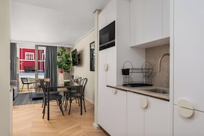 A modern kitchen with white cabinets, a built-in microwave, and a stainless steel sink. - Contemporary Sea Point Apartment | Walk to Beach (Cape Town)