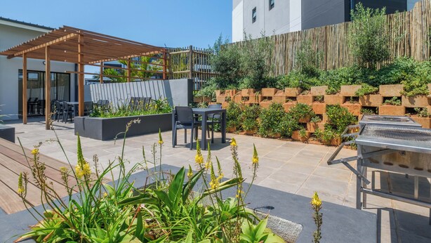 An outdoor patio with a pergola, seating area, and a barbecue grill. - Bliss Ballito | Comfort and Style 2x Bedroom (Dolphin Coast)