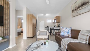 A modern living room with a round coffee table, a brown leather sofa, and a dining area in the background. - Bliss Ballito | Comfort and Style 2x Bedroom (Dolphin Coast)
