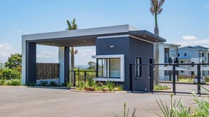 A modern building with a covered entrance, large windows, and a security gate. - Bliss Ballito | Modern Apartment and Clubhouse (Dolphin Coast)