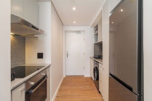 A compact kitchen with a built-in oven, microwave, and stainless steel range hood. - Dolce Vita | Designer Sea Point Apartment (Cape Town)
