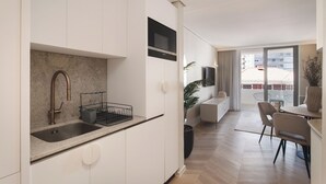 Una cucina moderna con piano di lavoro in granito, lavello in acciaio inossidabile e forno a microonde nero.