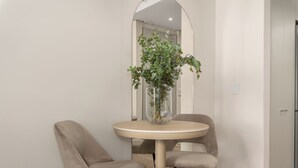 A dining area with a round table, two chairs, and a vase with green plants. - Dolce Vita | Designer Apartment | Lion's Head View (Cape Town)