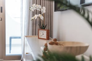 A room with a wooden clock, a bowl of decorative items, and a window with curtains. - Cozy Coastal Studio | Incredible Walkable Location (Cape Town)