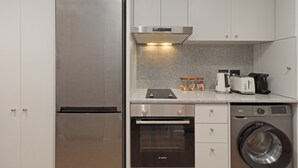 Eine kompakte Küche mit Edelstahlkühlschrank, Bosch-Backofen und Waschmaschine.