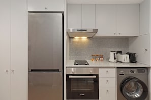 A compact kitchen with a stainless steel refrigerator, Bosch oven, and washing machine. - Cozy Coastal Studio | Incredible Walkable Location (Cape Town)