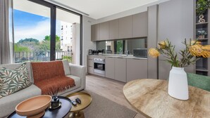 A modern apartment with a living area, kitchen, and balcony. - One Rosebank Premium Luxe Apartment (Johannesburg)