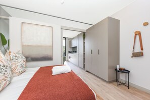 A modern bedroom with a large bed, a red rug, and a minimalist design. - One Rosebank Premium Luxe Apartment (Johannesburg)