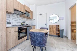 Een moderne keuken met houten kastjes, een inbouwoven en een ronde spiegel aan de muur.
