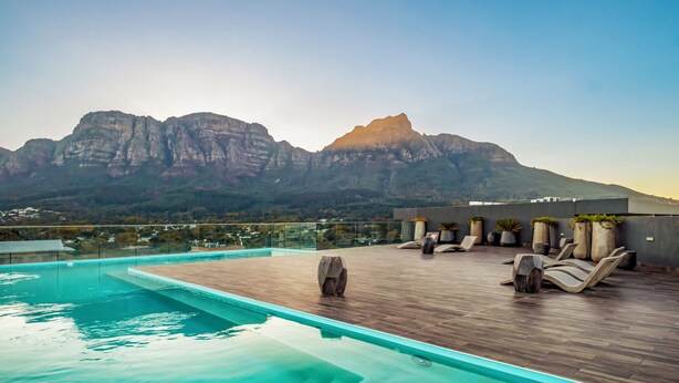 Ein Pool auf dem Dach mit Blick auf die Berge, Liegestühle und Topfpflanzen.
