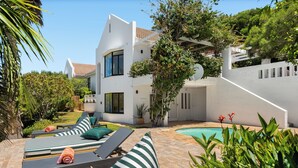 A modern house with a swimming pool, outdoor seating, and lush greenery. - 5BD Villa with Mountain Views, Pool and Braai (Cape Town)