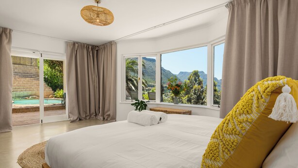 A bedroom with a large bed, a view of a swimming pool, and a mountain landscape. - 5BD Villa with Mountain Views, Pool and Braai (Cape Town)