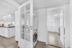 Eine moderne Küche mit weißen Schränken, einer Mikrowelle und einer Waschmaschine.