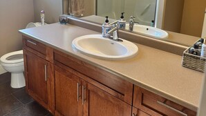 A bathroom with a wooden vanity, a white sink, a mirror, and a glass shower enclosure.