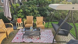 An outdoor patio area with wicker chairs, a glass table, and a swing chair.