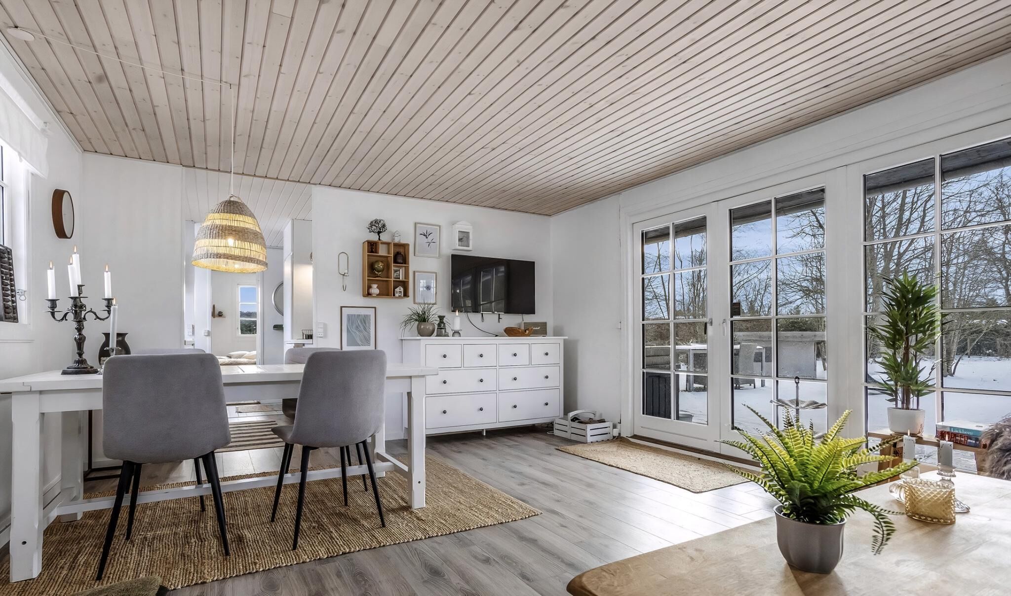 A modern kitchen with white cabinetry, a dining area with two chairs, and a large window offering a view of the outdoors.