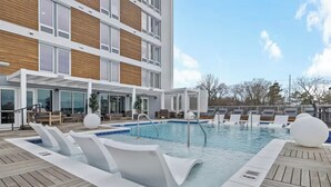 A modern hotel pool area with a rectangular pool, lounge chairs, and a wooden deck. - Nashville KING BED, Gym, Rooftop Pool, Parking (Nashville)