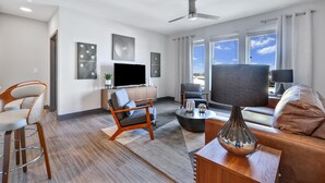 A modern living room with a flat-screen TV, two sofas, a coffee table, and a ceiling fan. - Nashville KING BED, Gym, Rooftop Pool, Parking (Nashville)