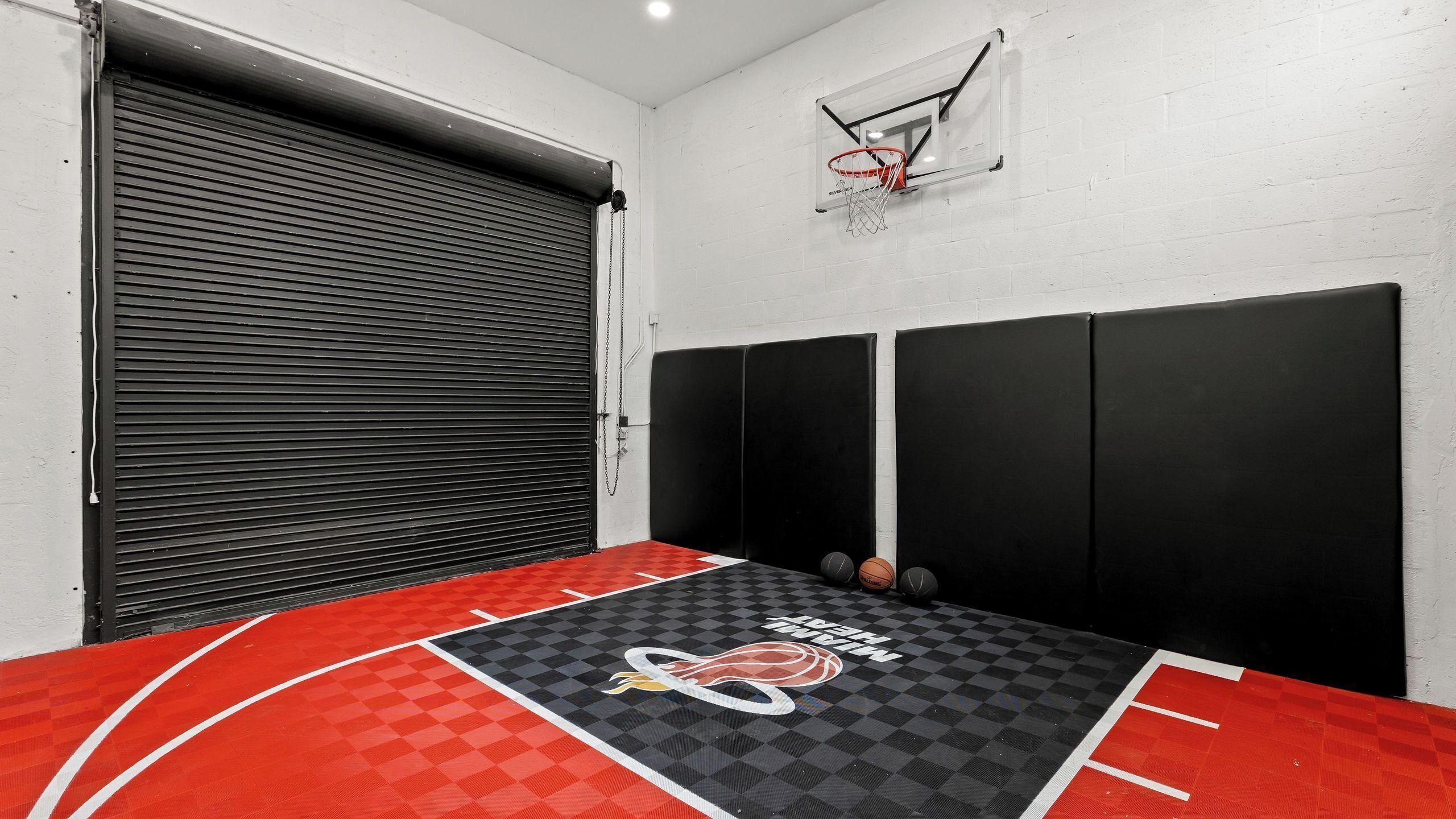 Ein Basketballfeld mit Miami Heat Logo, einer heruntergelassenen Rolltür und einem Basketballkorb.