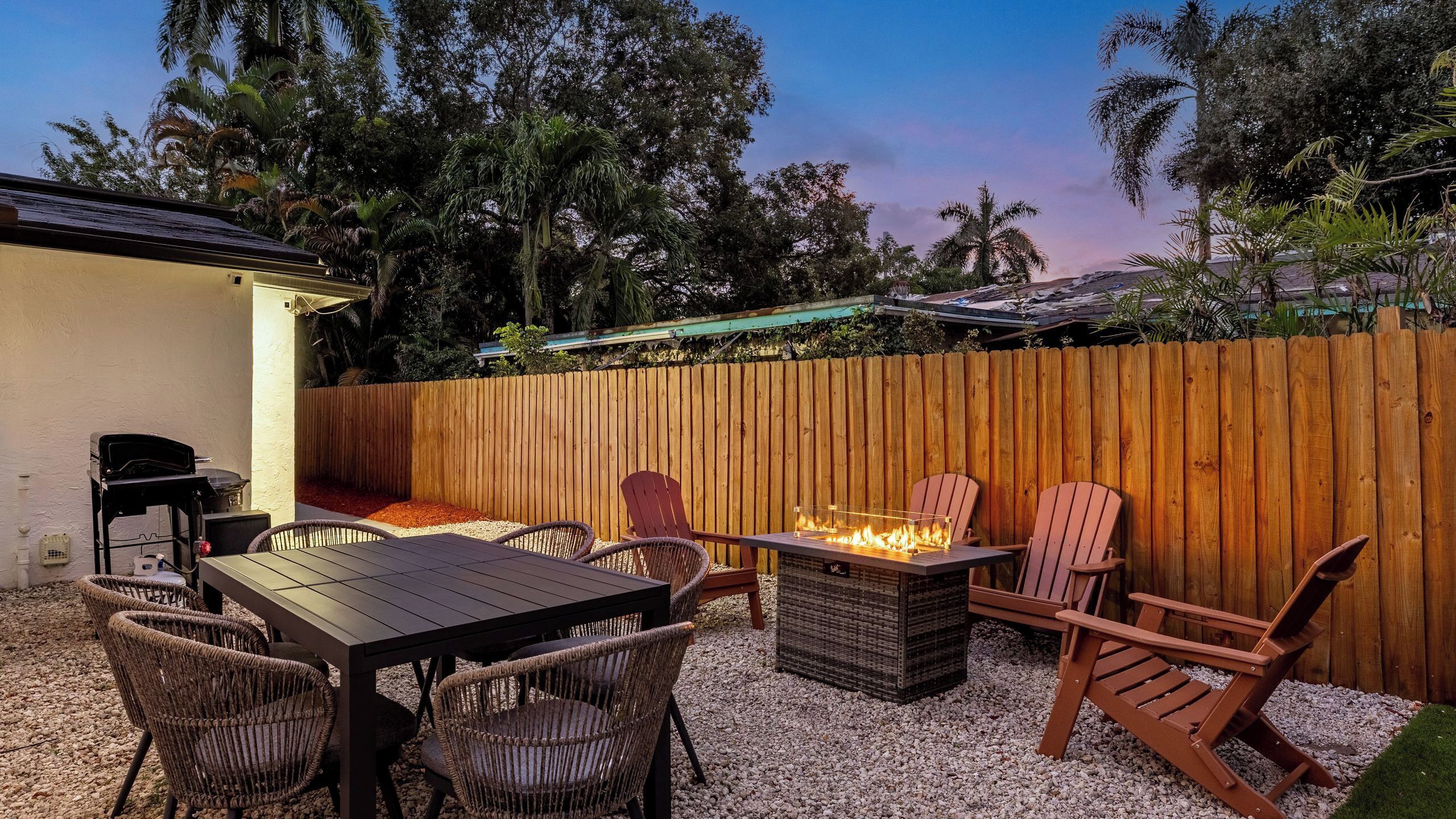 A patio with a table and chairs, a fire pit, and a wooden fence.