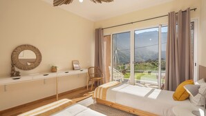 Ein Schlafzimmer mit zwei Betten, einem Schreibtisch, einem Stuhl und einem großen Fenster mit Bergblick.