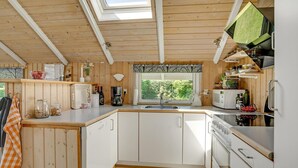 A compact kitchen with wooden cabinetry, a built-in microwave, and a window overlooking greenery. - 3 bedroom beautiful home in Hejls (Hejls)