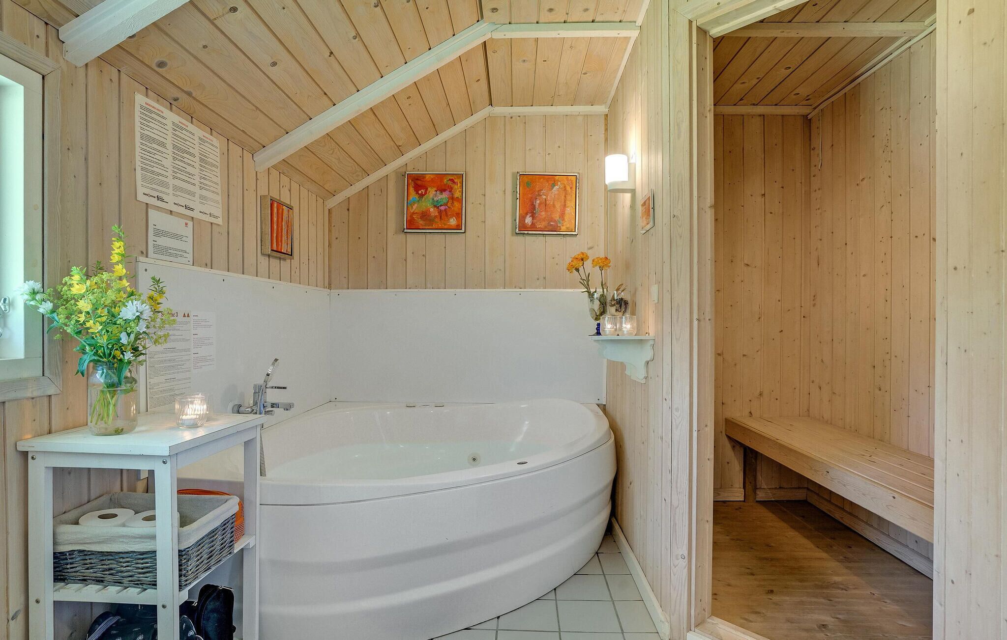 A wooden cabin with a large white bathtub, a small sink, and a shelf with flowers.