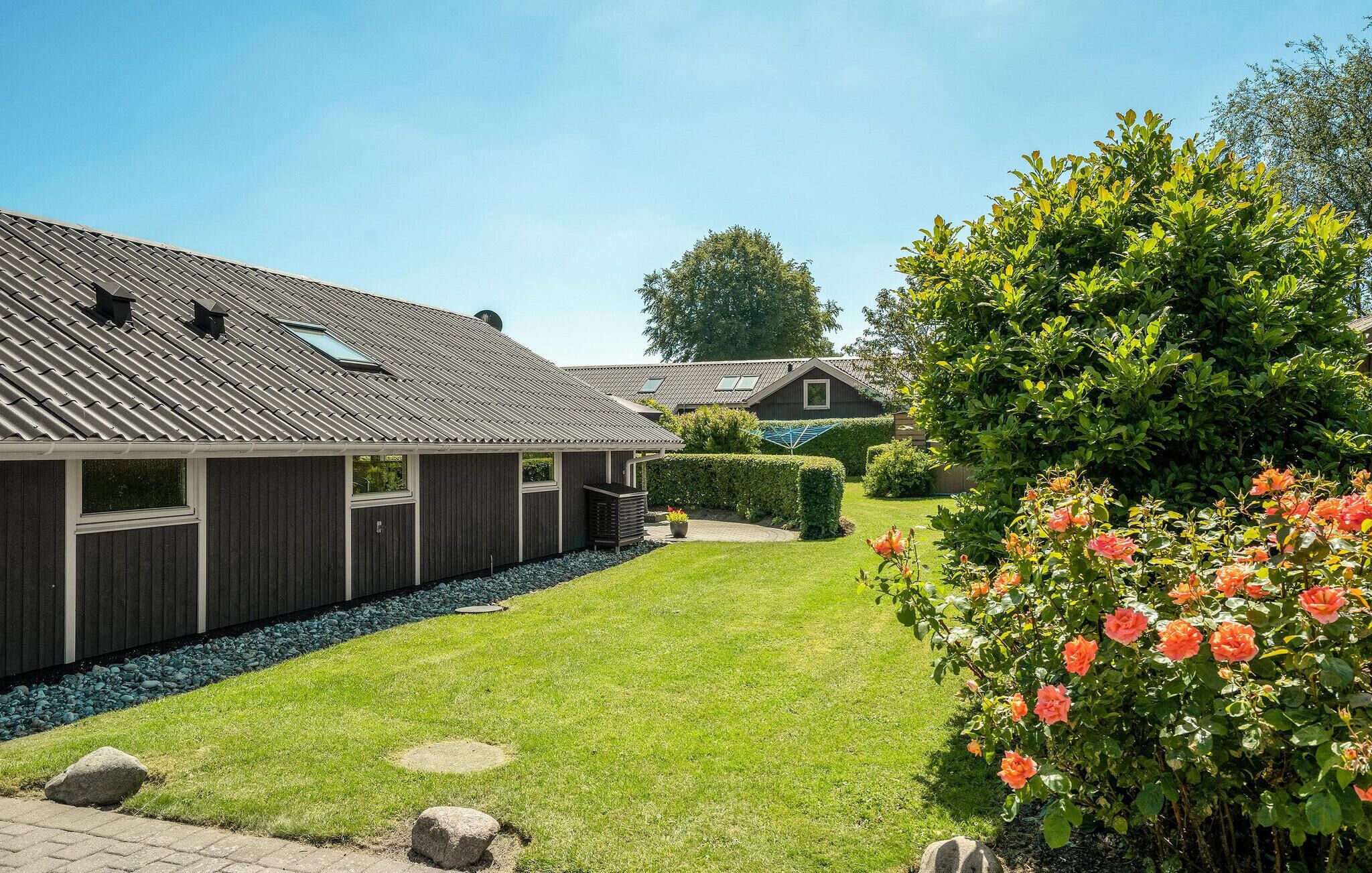 A modern building with a sloped roof, a well-maintained lawn, and a rose bush.