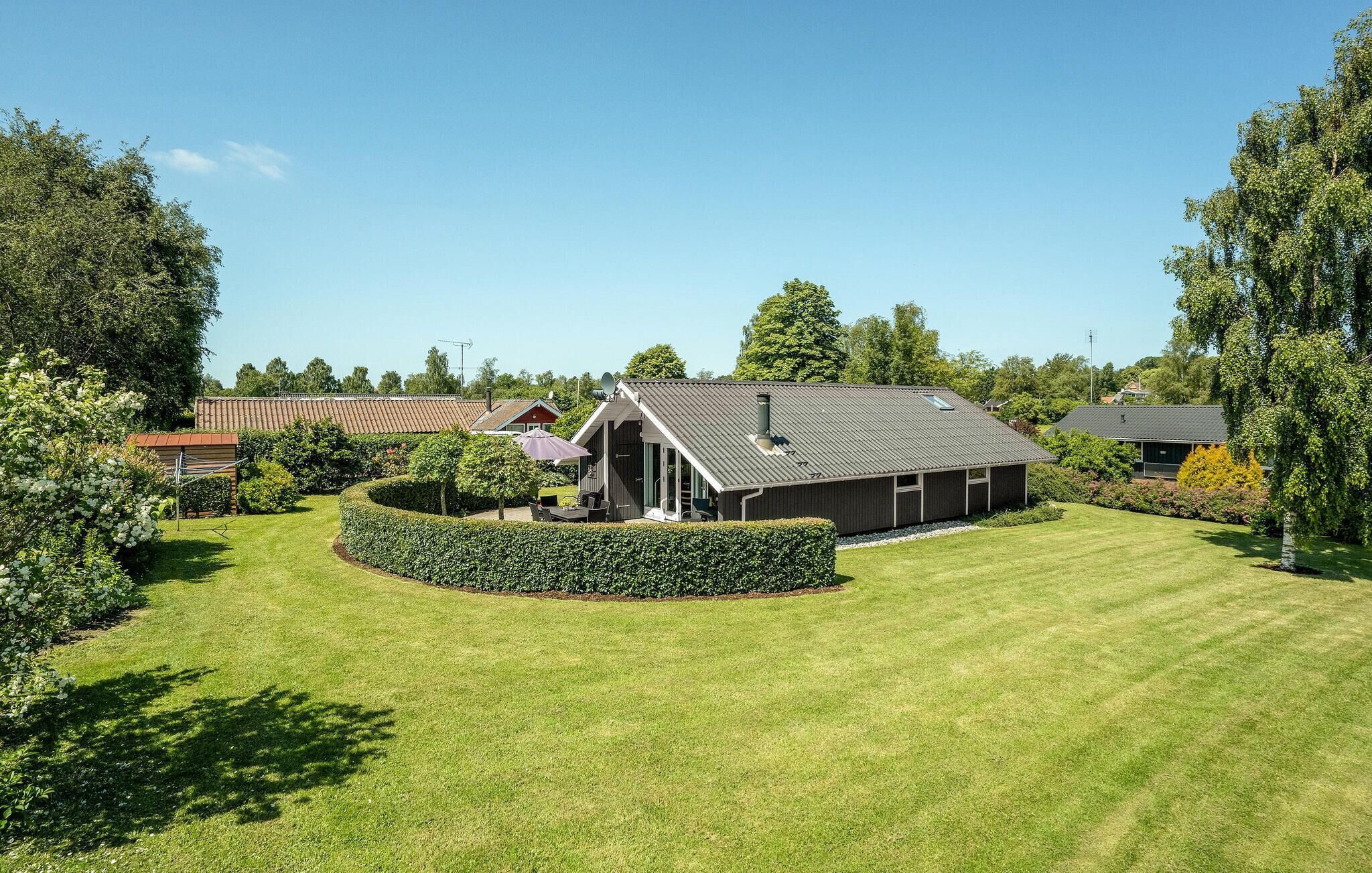 A modern house with a sloped roof, a covered patio, and a well-maintained lawn.