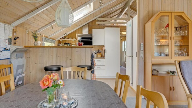 A cozy kitchen with wooden cabinets, a dining table with chairs, and a glass cabinet with dishes. - 3 bedroom beautiful home in Hejls (Hejls)
