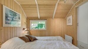 A bedroom with a wooden ceiling, a large bed with white bedding, a window with a view of greenery, and a framed picture on the wall. - 3 bedroom beautiful home in Hejls (Hejls)