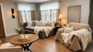 Ein gemütliches Wohnzimmer mit einer Sofagarnitur, einem runden Couchtisch und einer Lampe.