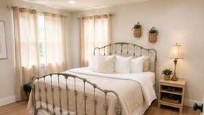 Ein Schlafzimmer mit einem Metallbettgestell, einem Nachttisch mit Lampe und zwei Wandkörben.