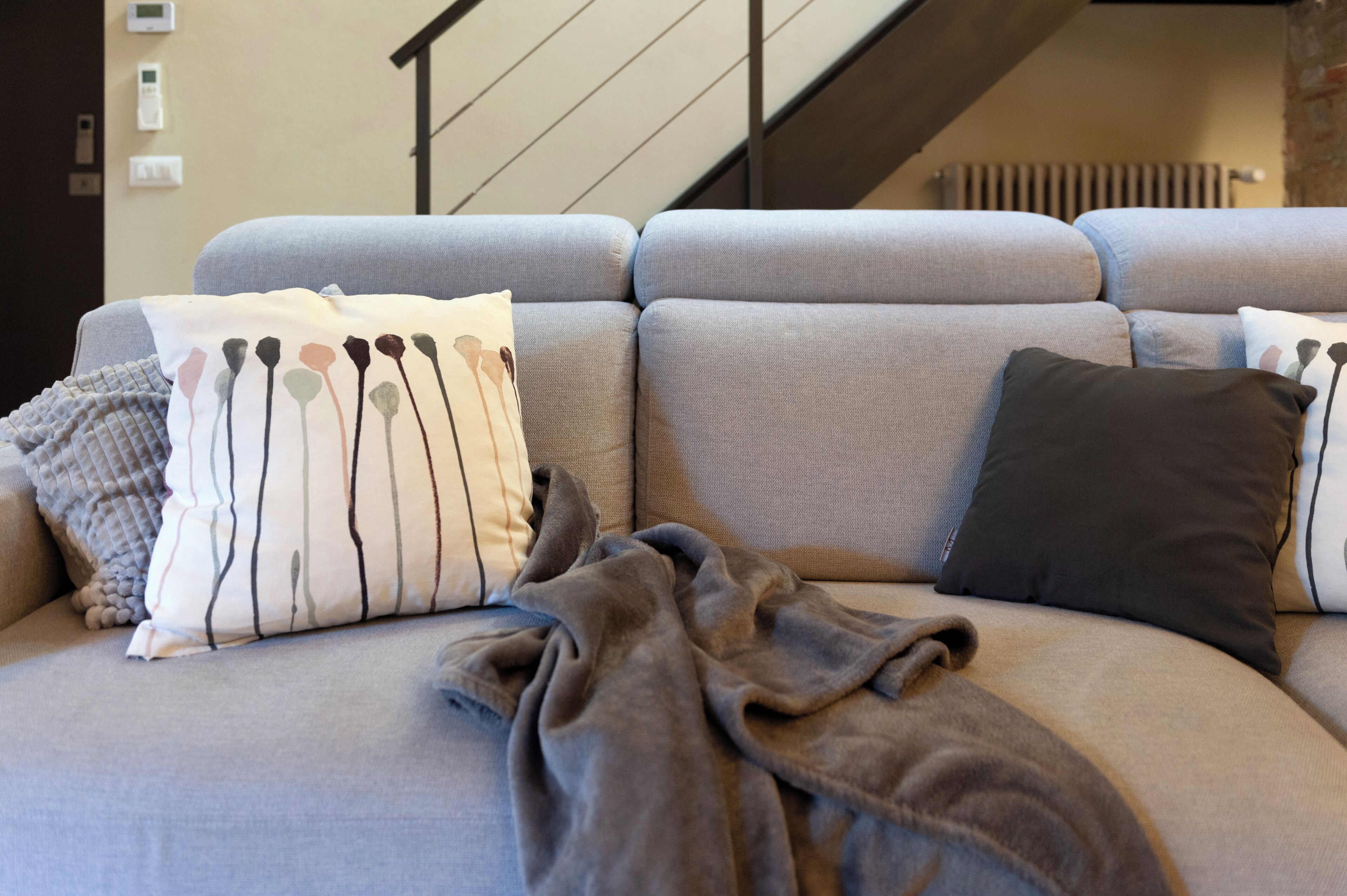 Un canapé gris agrémenté de plusieurs coussins et d’une couverture.