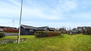 A modern two-story house with a sloped roof, surrounded by a well-maintained lawn and a hedge.