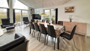 A spacious dining area with a long table, multiple chairs, a television, and a cabinet.