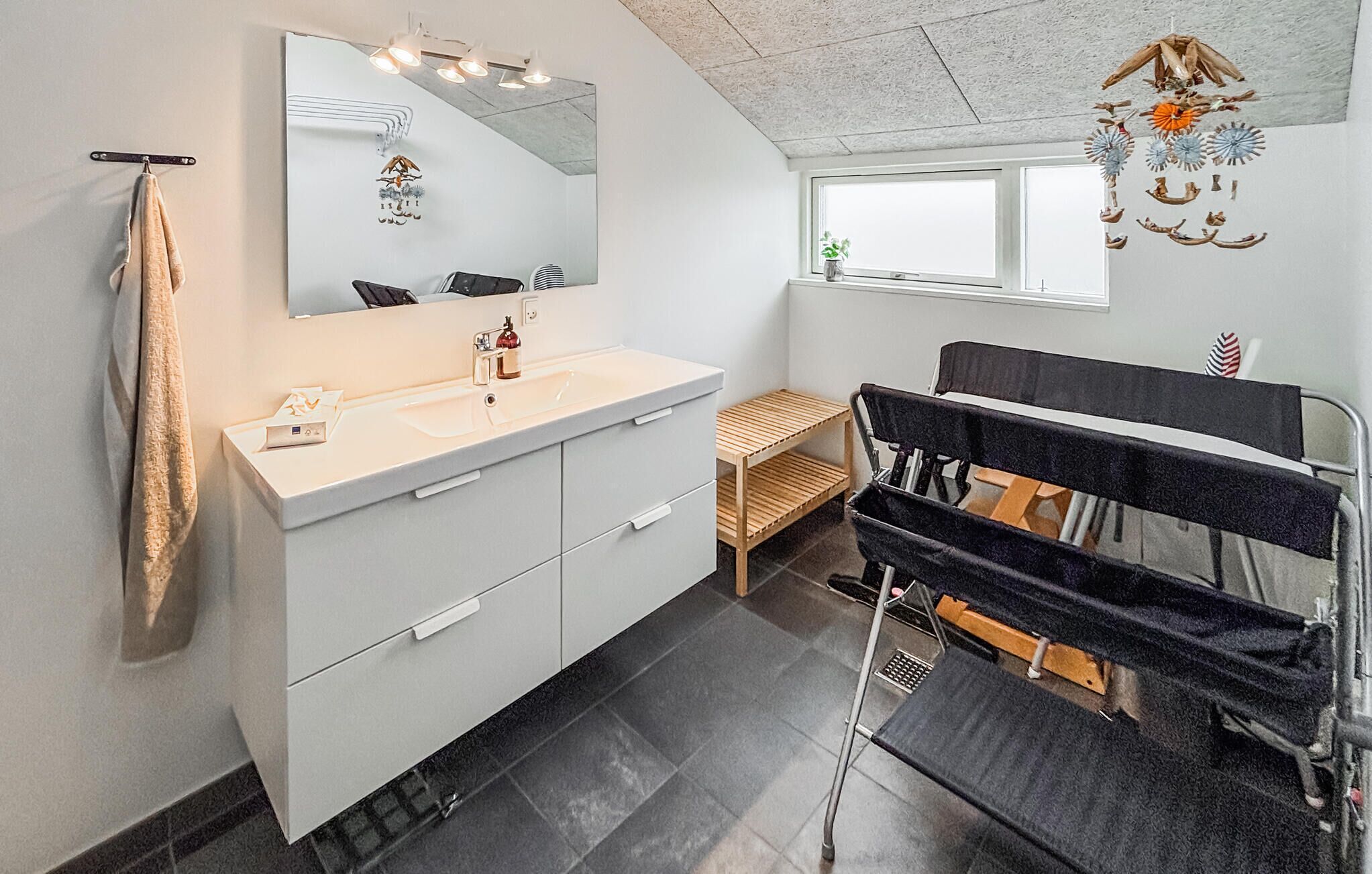 A modern bathroom with a white vanity, a large mirror, a towel rack, and a window with a view.