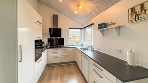 A modern kitchen with white cabinets, a black countertop, and a window providing natural light.
