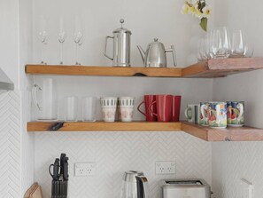 Eine Küche mit drei Holzregalen, auf denen sich Küchenutensilien wie Gläser, Tassen und ein Toaster befinden.