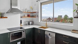 A modern kitchen with a large window, built-in appliances, and a view of the city. - Coogee Oasis Ocean Outlooks near the Beach (Coogee)