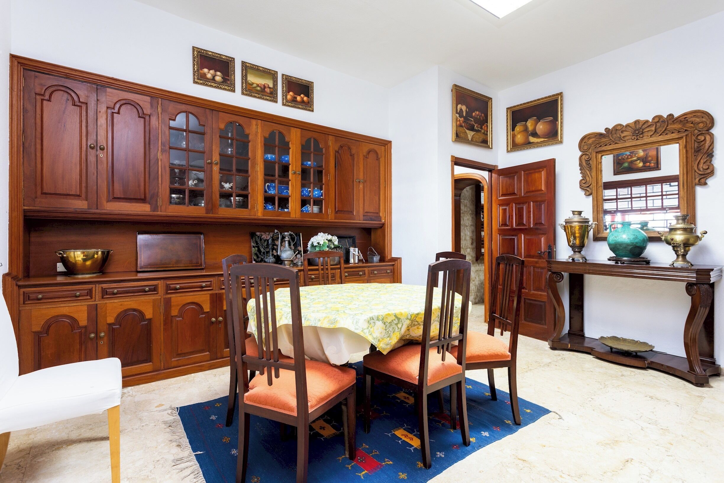 Un comedor con armarios de madera, una mesa con mantel y sillas.