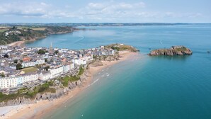 A coastal town with a prominent church, sandy beaches, and a rocky outcrop. - 6 Paragon Court - Sea Front Apartment (Tenby)