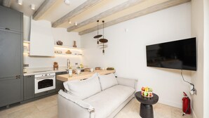 Eine moderne Küche mit Backofen, ein Essbereich mit einer Couch und einem an der Wand befestigten Flachbildfernseher.