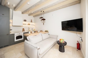 Eine moderne Küche mit Backofen, ein Essbereich mit einer Couch und einem an der Wand befestigten Flachbildfernseher.