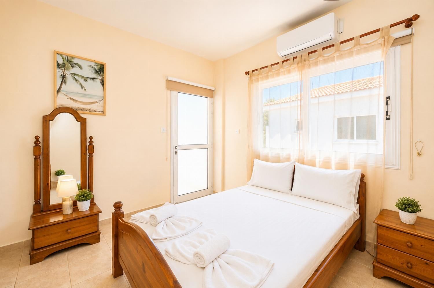 Een slaapkamer met een bed, een houten dressoir, een spiegel, een raam met gordijnen en een airconditioning.